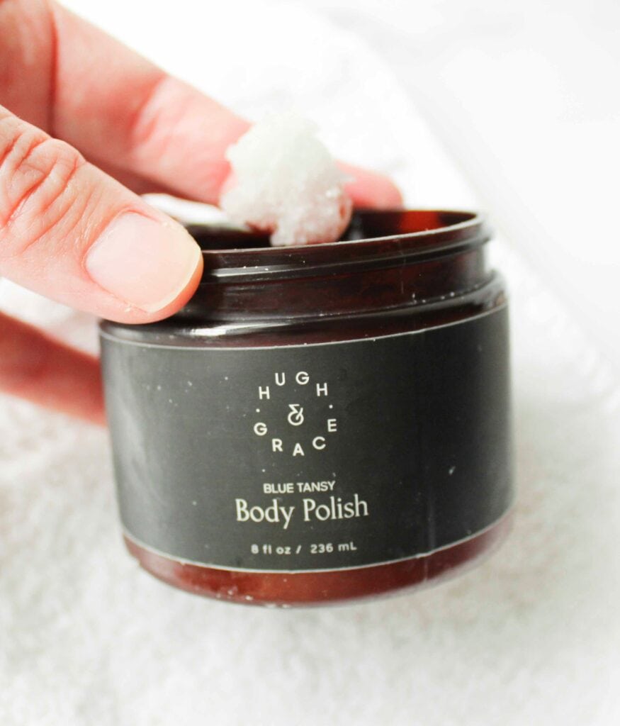 Hand scooping out some of Hugh and Grace Body Polish to show texture.
