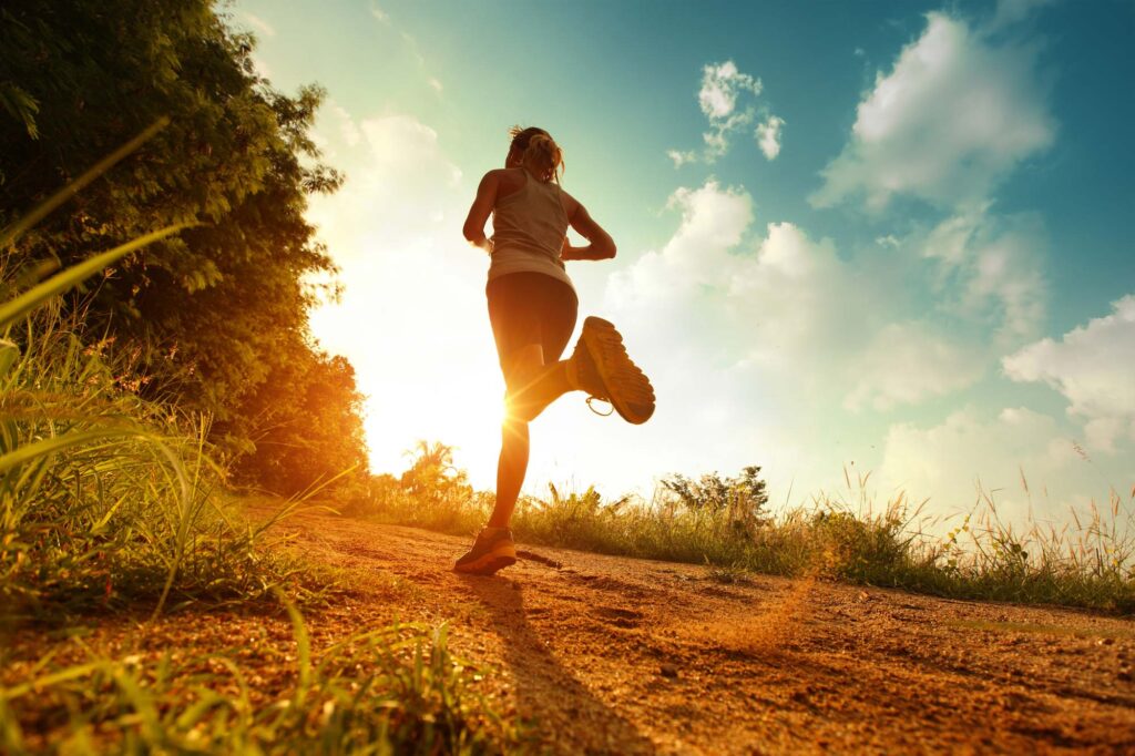 Woman running in nature on dirt with blue sky in background