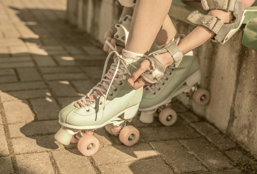 Zoom in on roller skates while woman is lacing them up while wearing protective gear
