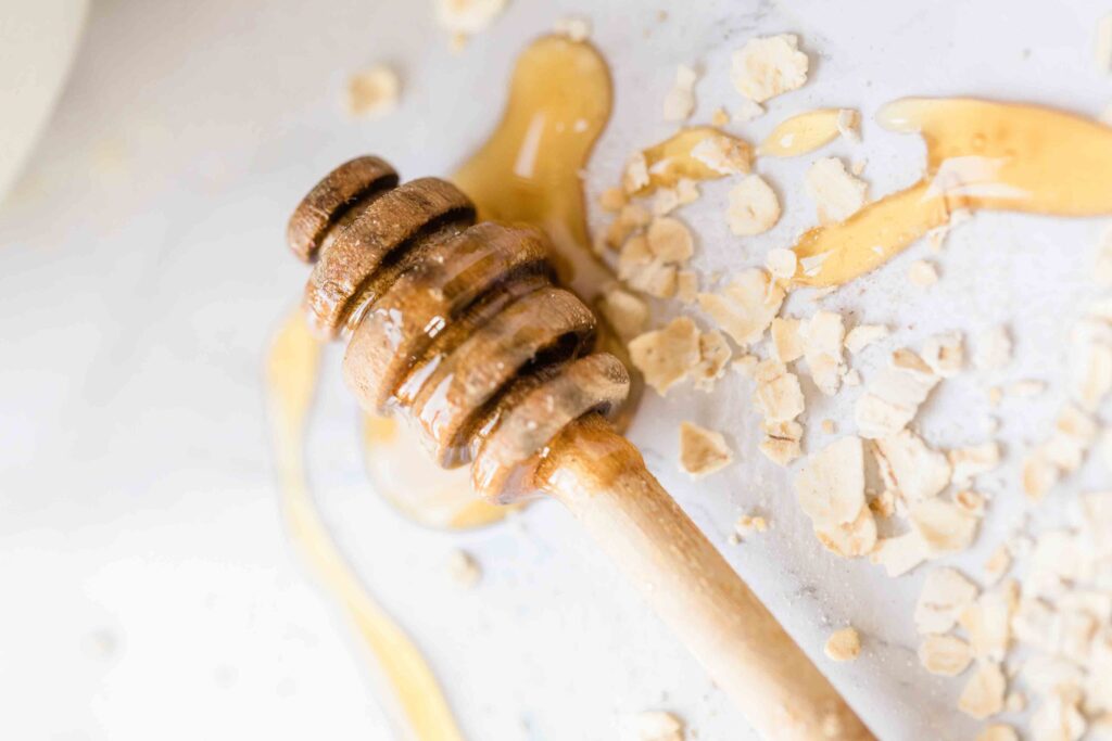 honey scoop and raw oats on parchement paper with honey dripped around