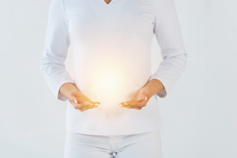 Cropped view of healer standing wearing white and gesturing near light isolated at abdomen