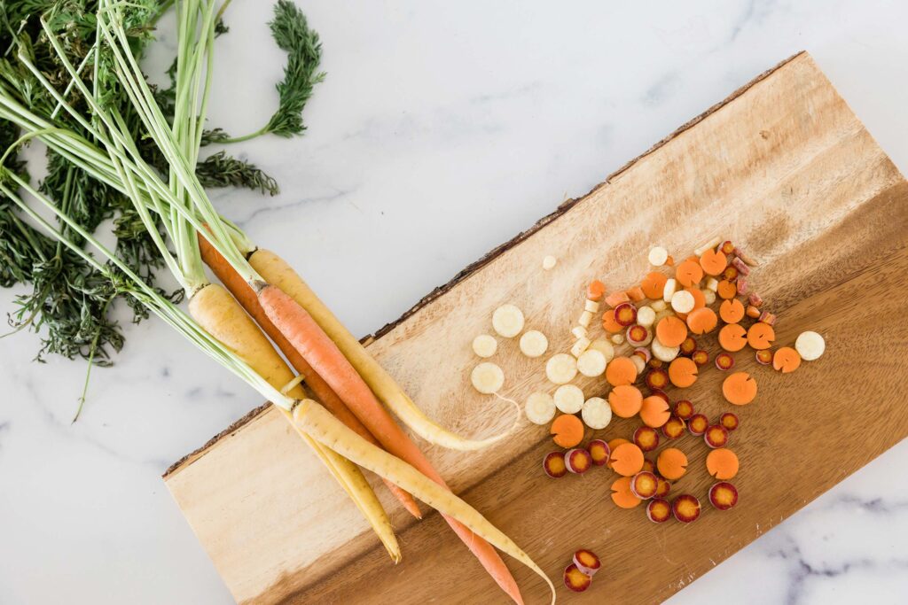 Orange and yellow carrots with stems on a wood cutting board over while counter