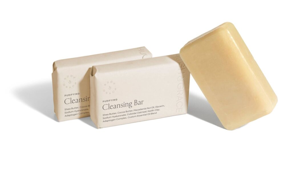 Two moisturizer bar soaps in packaging with one soap out of package on white counter