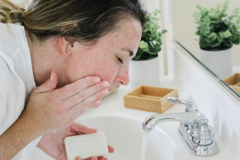 woman washing face in sink with hugh and grace bar soap