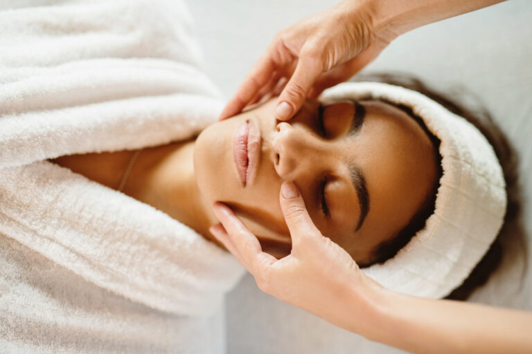 Woman wearing white robe on table getting a facial