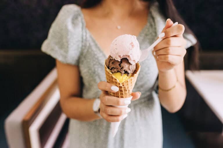 zoomed in view on ice cream cone with woman in gray dress holding