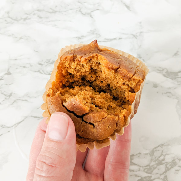 hand holding an open paleo pumpkin muffin to show fluffy inside texture