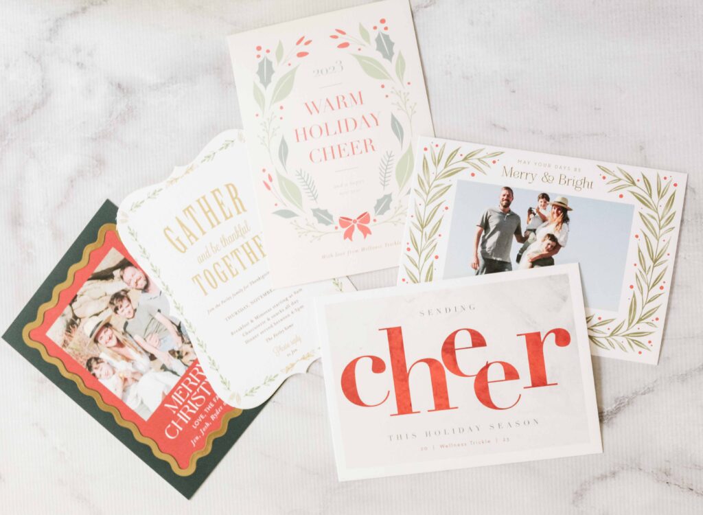 Various personalized christmas cards and an event invite sitting on a marble counter.