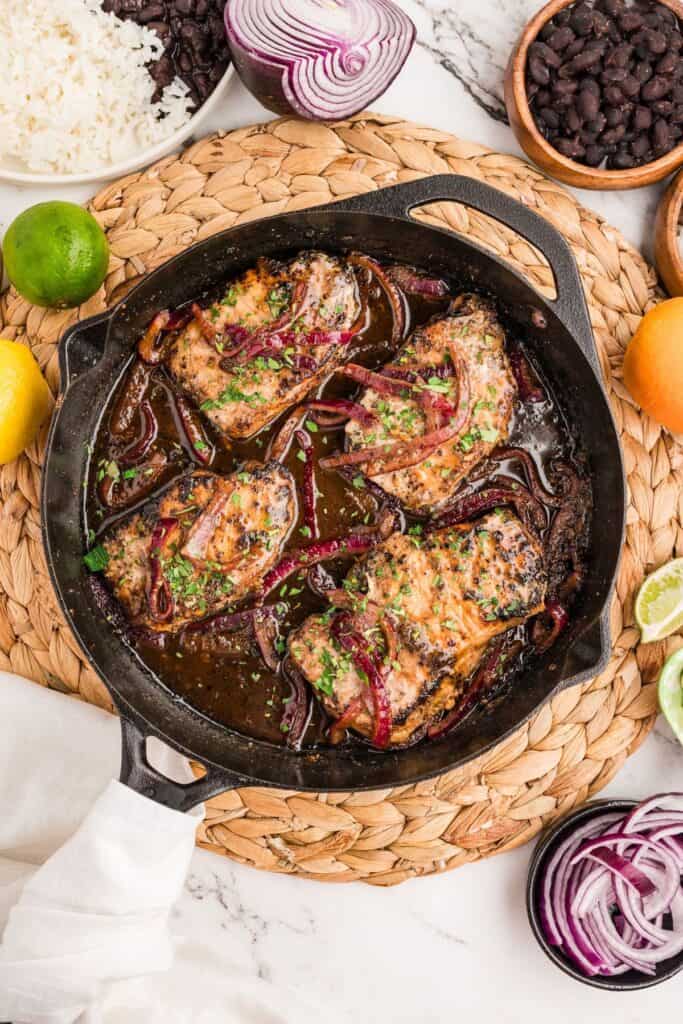Resting finished pan-seared pork chops in cast iron skillet.