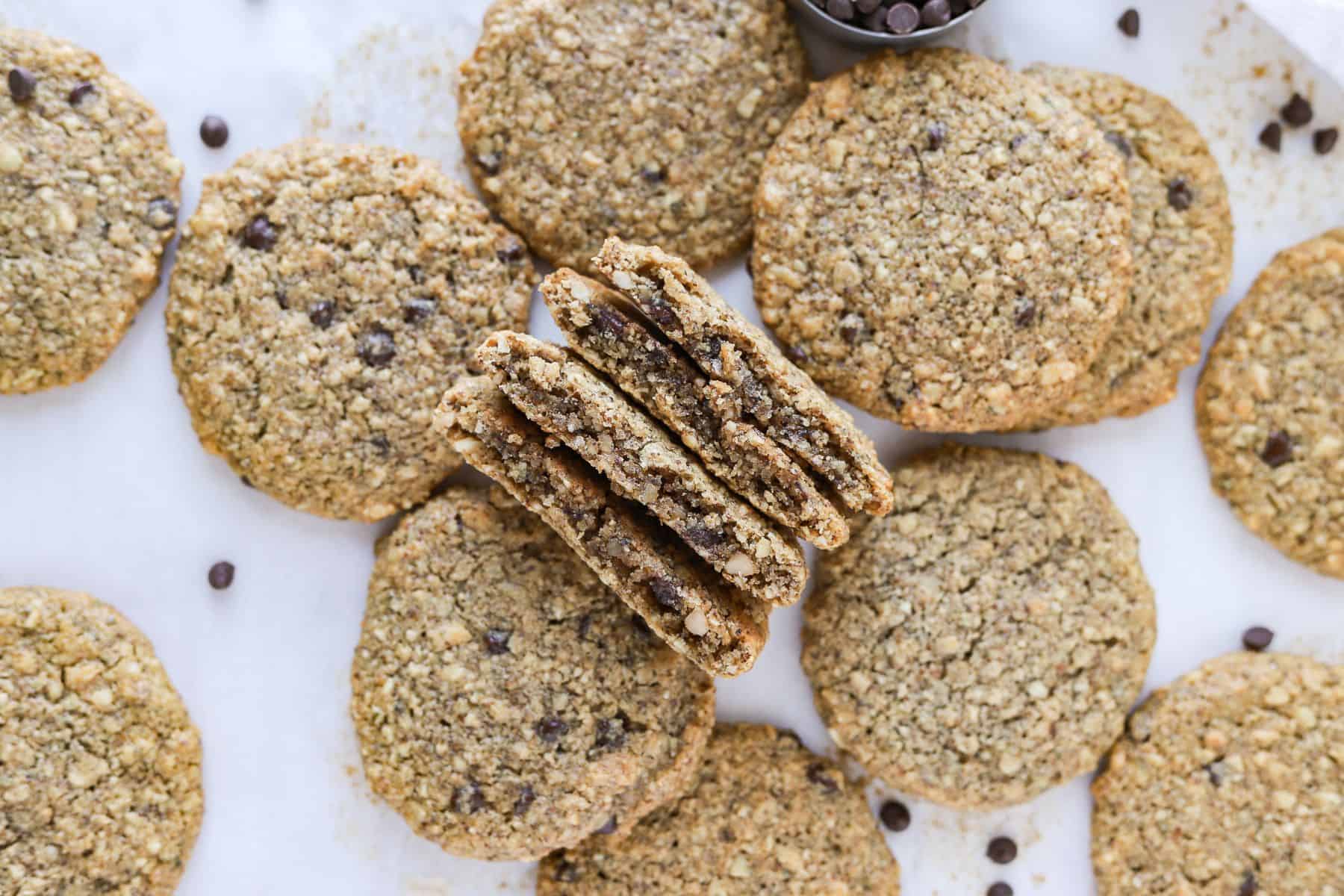 Almond flour oatmeal breakfast cookies on parchment paper with two broken open to show inside texture.