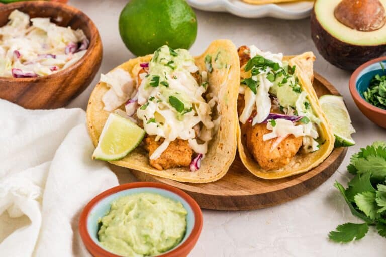 Gluten free fish tacos on wooden serving platter with toppings.