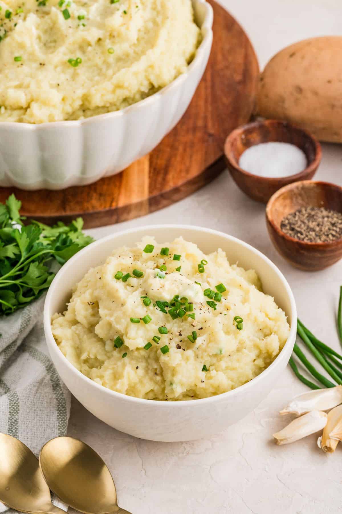 Mashed white sweet potatoes in a bowl topped with fresh chopped chives.