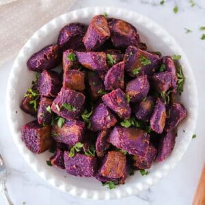 Close up of roasted purple sweet potatoes in serving bowl.