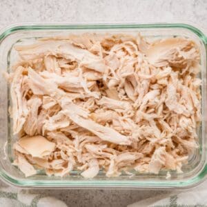 Close up of brined Dutch oven shredded chicken in a meal prep container.
