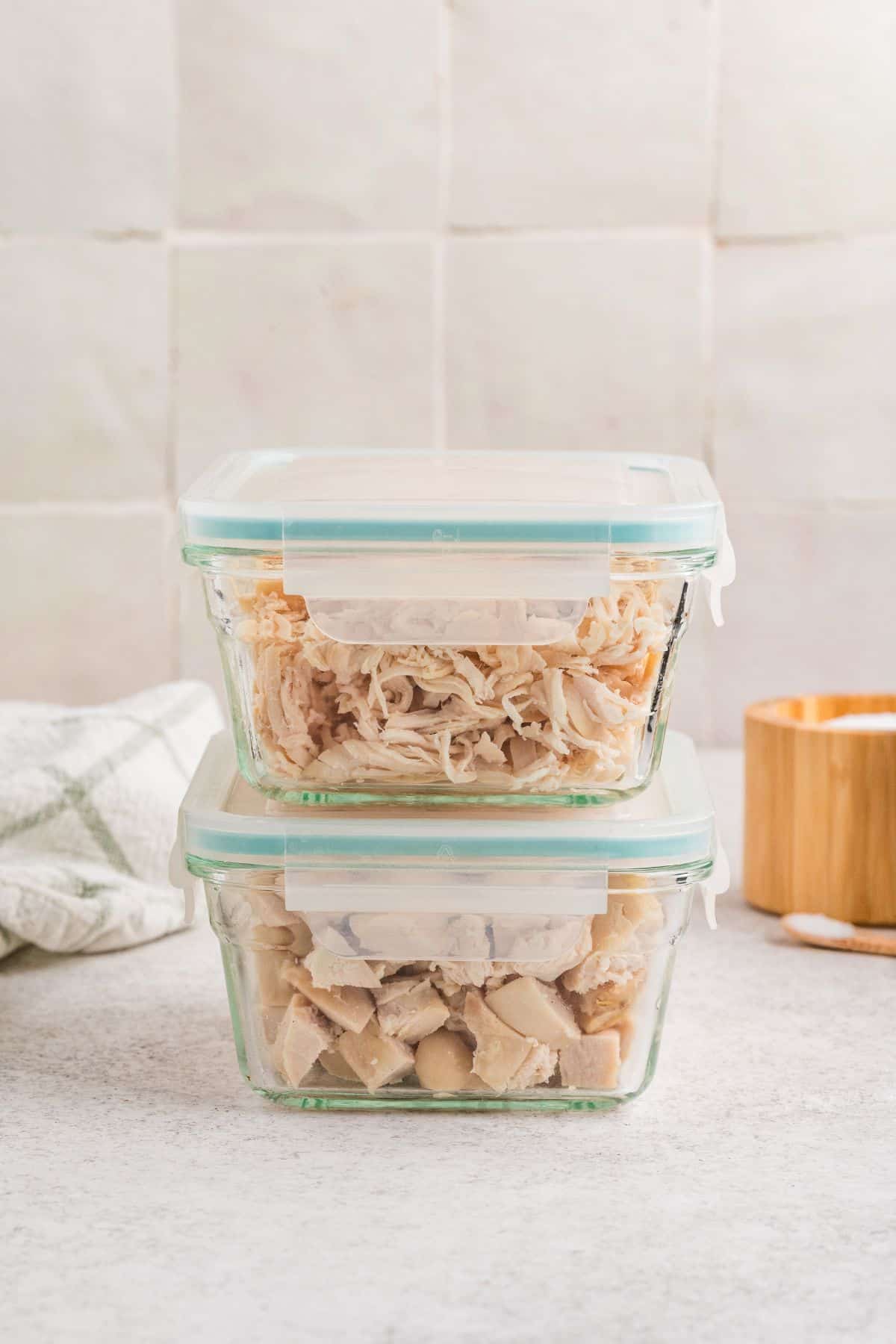 Two glass containers stacked with Dutch oven chicken for meal prep.