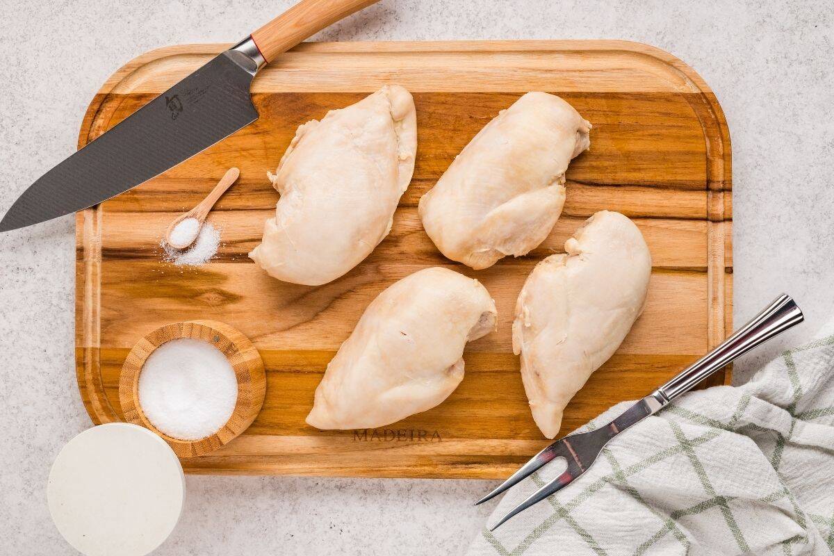 Dutch oven chicken breasts on a cutting board ready to be shredded and added to meal prep containers.