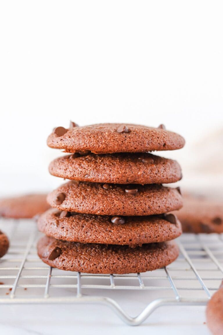 Gluten free double chocolate chip cookies stacked on a cooling rack.