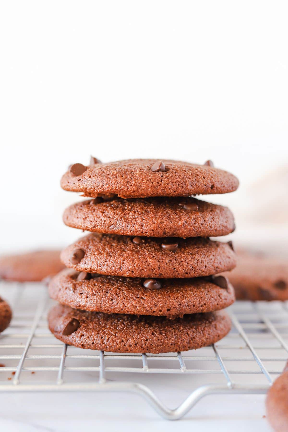Gluten free double chocolate chip cookies stacked on a cooling rack.