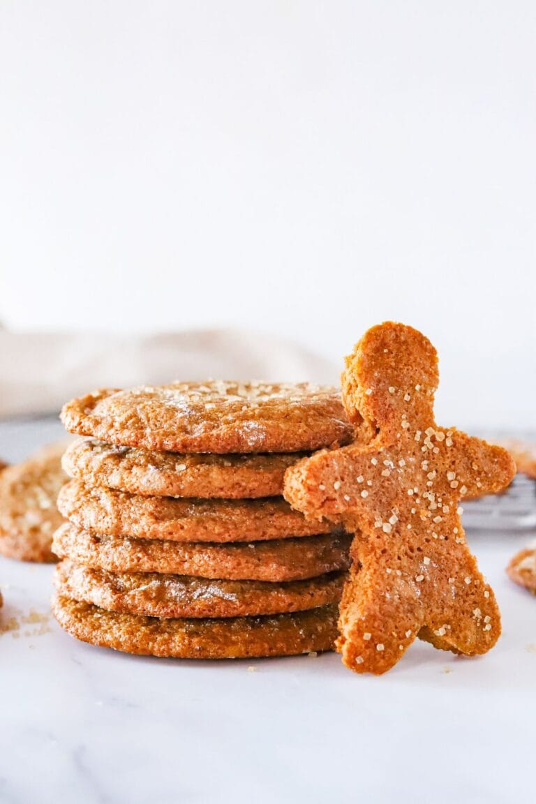 Gluten free ginger molasses cookies stacked on a counter with a gingerbread man cut out.