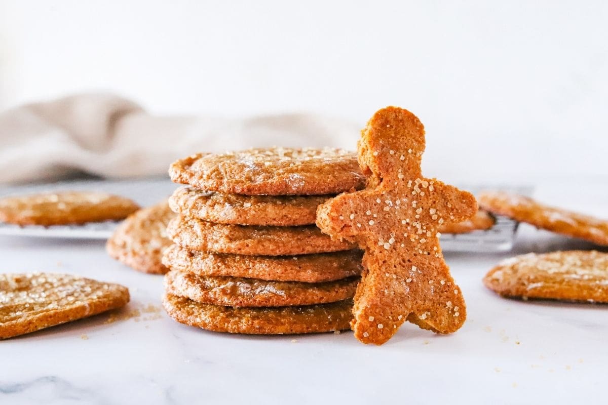 Gluten free ginger molasses cookies stacked on a counter with a gingerbread man cut out made with the same cookie dough.