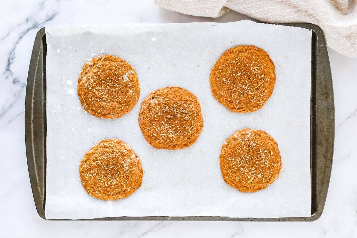 Gluten free ginger molasses cookies fresh baked on a baking sheet lined with parchment paper.