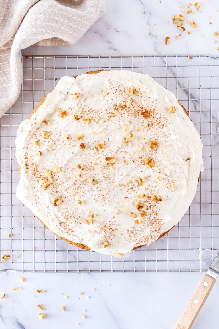 Gluten free spice cake frosted with dairy free cream cheese on top of a cooling rack.