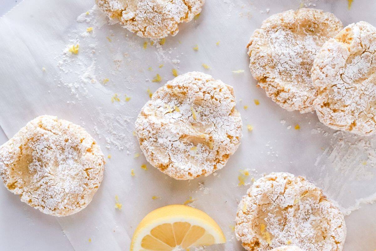 Gluten free lemon cookies on parchment paper with lemon zest sprinkled on top.