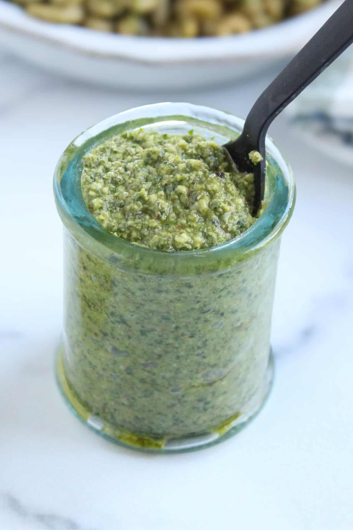 Dairy free walnut pesto in a glass jar on the counter to be added to pasta.