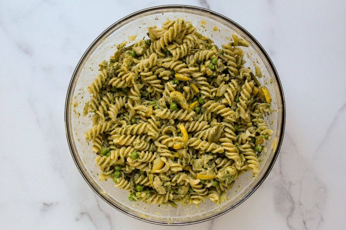 Gluten free pesto pasta salad just mixed in a glass storage bowl.
