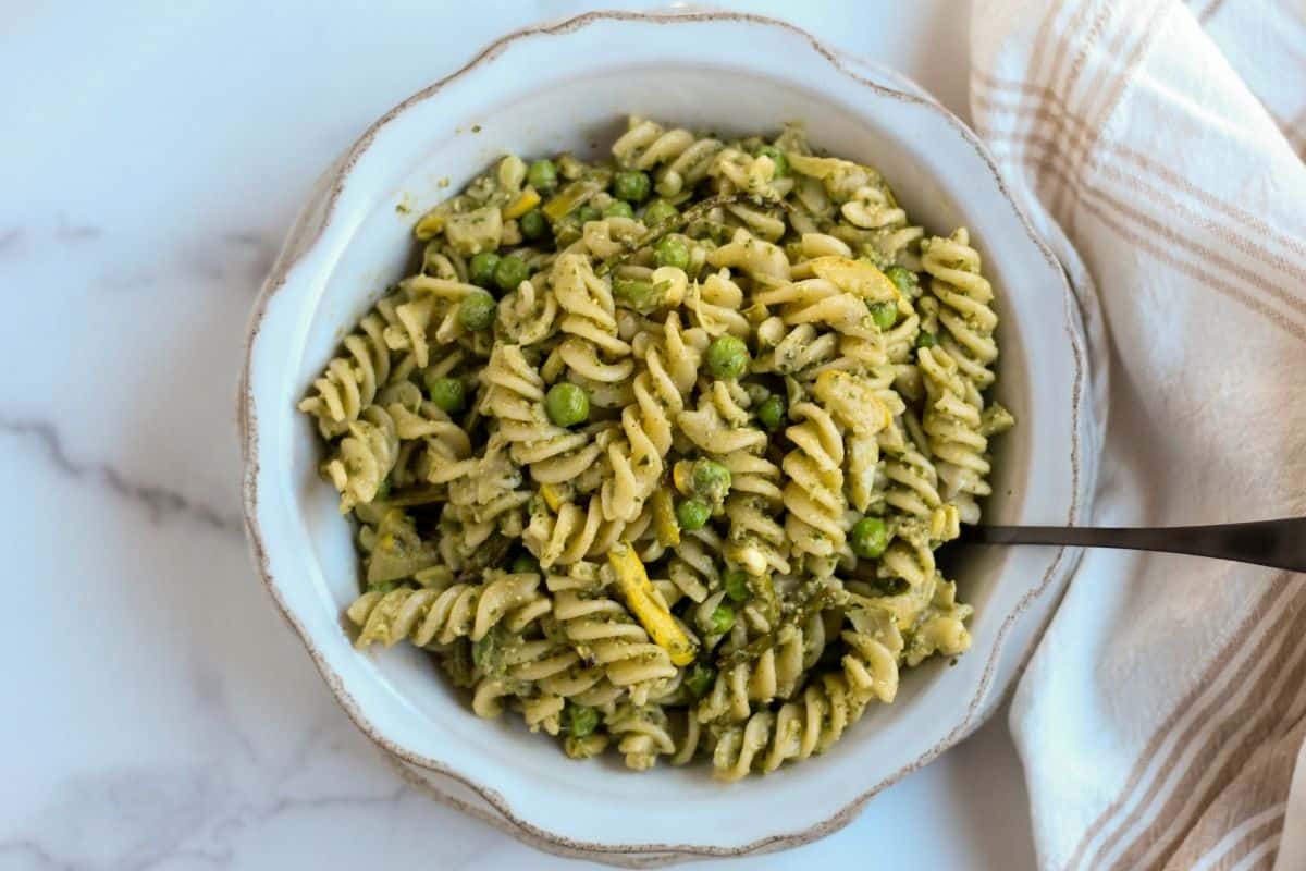 A bowl of gluten free pesto pasta salad in a bowl with a fork for serving.