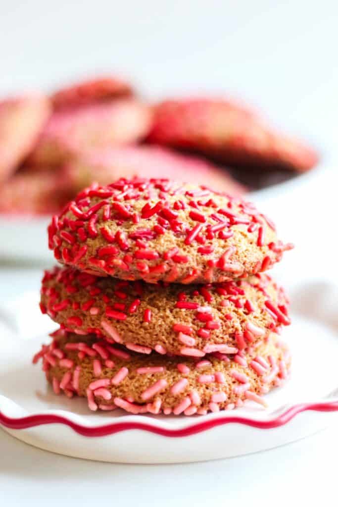 Three gluten free sprinkle cookies stacked on a plate.