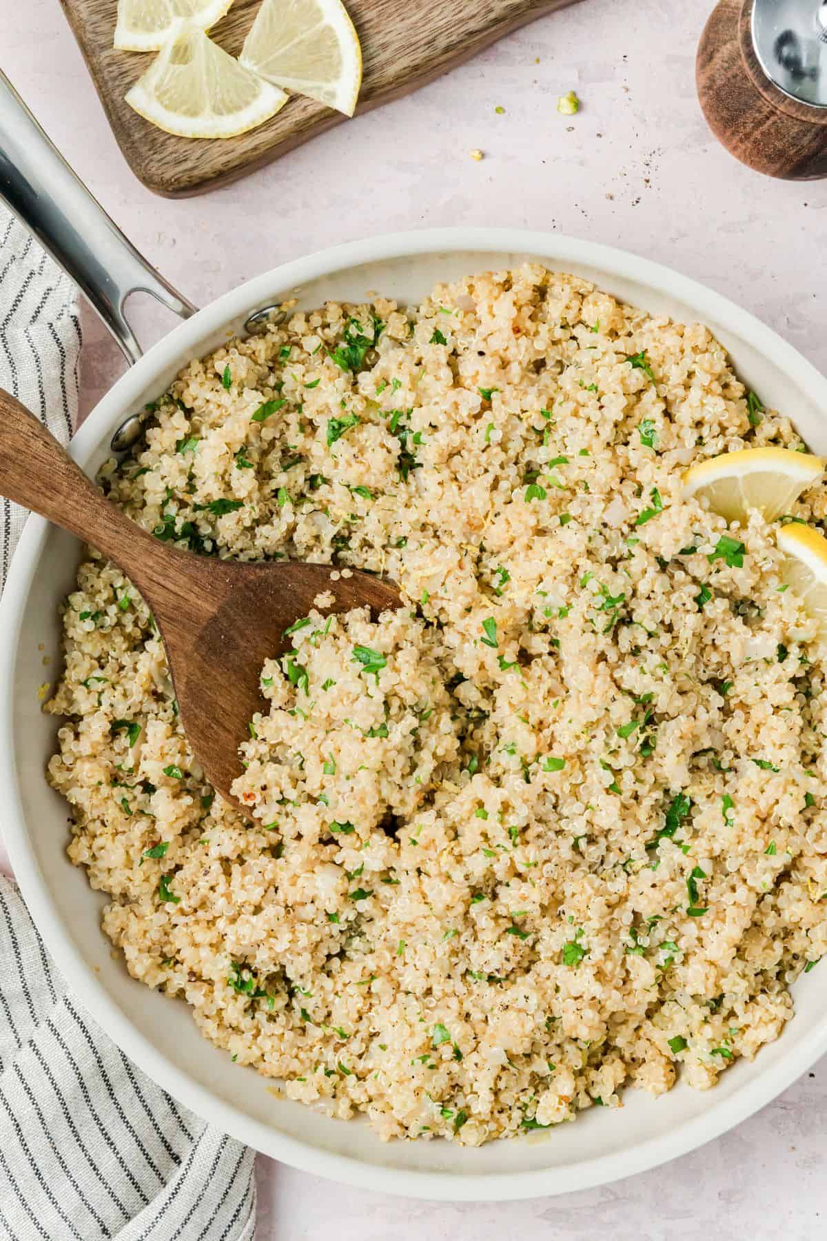Lemon herb quinoa in a skillet being served at the table.