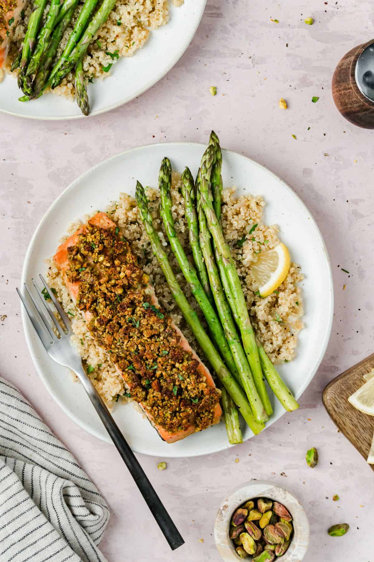 A plate of pistachio crusted salmon, asparagus and lemon herb quinoa on the table for serving.